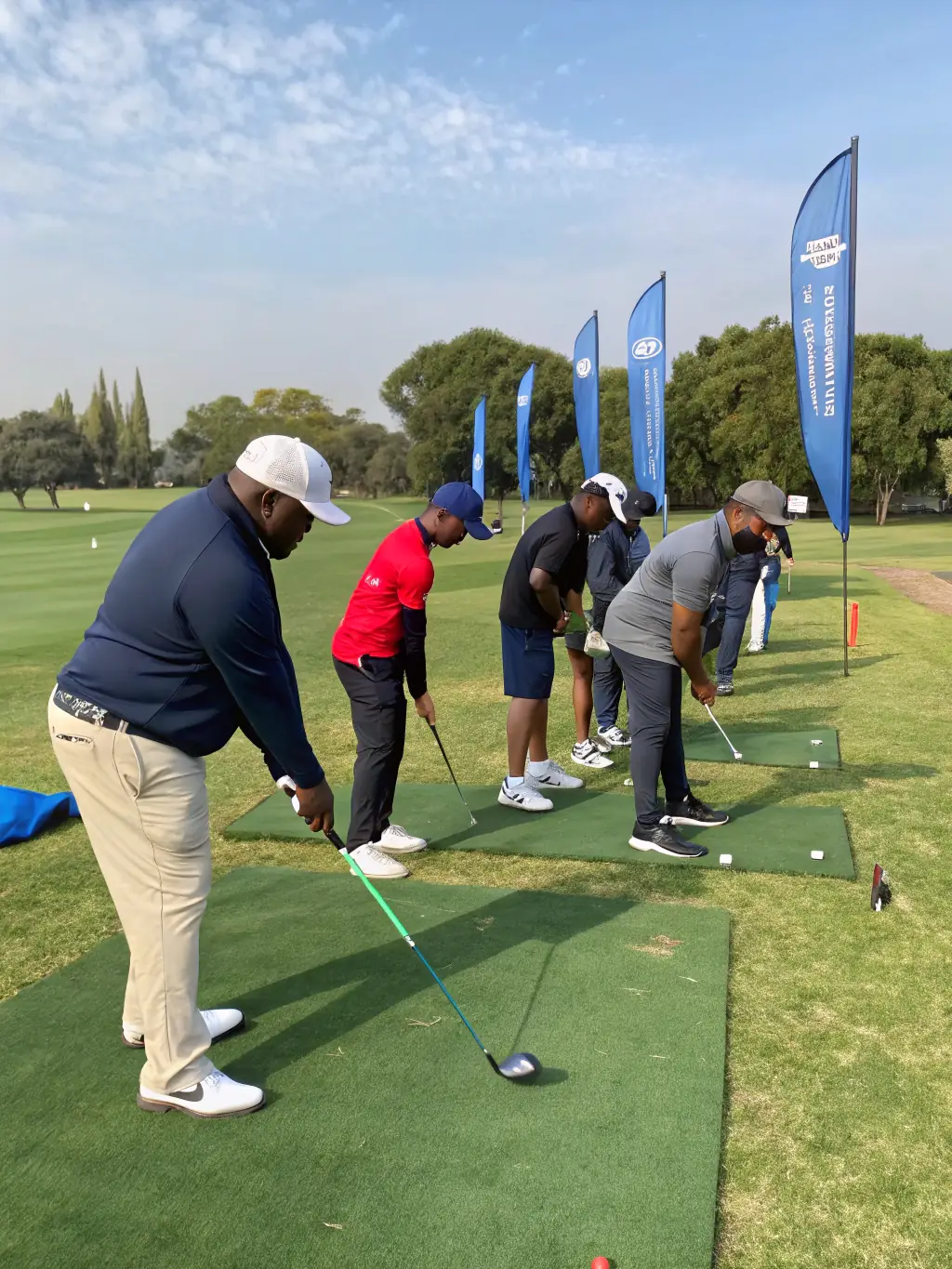 A diverse group of adult golfers participating in a group lesson, with the instructor providing personalized feedback.